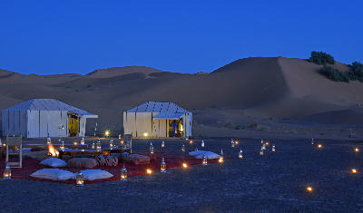 Night view of a luxury desert camp in the Erg Chebbi dunes near Merzouga, Morocco.