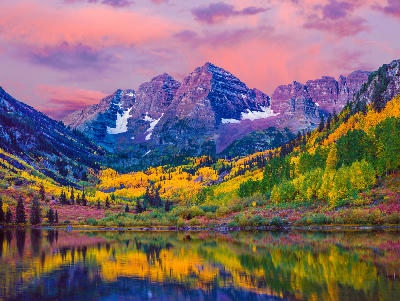Maroon Bells reflected in Maroon Lake at sunrise with autumn aspens in Aspen Colorado