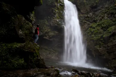Visitor standing beside the powerful cascade of Palovit Waterfall as it plunges through a moss-covered rocky gorge in Rize, Turkey.