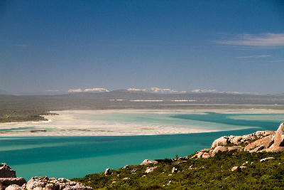 Panoramic view of Langebaan Lagoon with turquoise waters, white sandbanks and distant Cederberg mountains in West Coast National Park, South Africa.