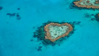 Aerial view of the naturally heart-shaped Heart Reef surrounded by turquoise water in the Great Barrier Reef, Queensland.
