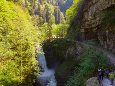 Palovit Waterfall plunging through a steep forested gorge, with visitors overlooking the cascade from a path in the Kaçkar Mountains of Rize, Turkey.