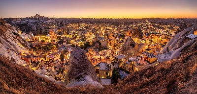 Panoramic twilight view of Göreme Town in Cappadocia with illuminated cave hotels, fairy chimneys and rock-cut architecture.