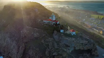 Cape St. Blaize Lighthouse perched on cliffs above The Point in Mossel Bay at sunset, South Africa.