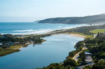 View across the Touw River Estuary at Wilderness where calm estuarine waters meet beaches, dunes and the Indian Ocean along South Africa's Garden Route.