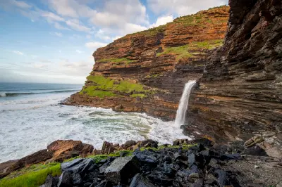 Waterfall Bluff waterfall cascading over stratified coastal cliffs into the ocean below on South Africa's Wild Coast.