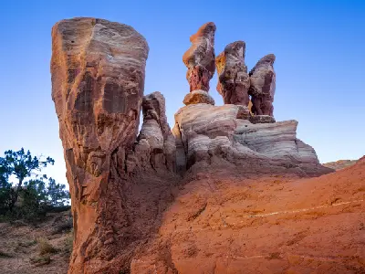 Tall weathered sandstone hoodoos and sculpted rock formations glow in warm sunset light at Devil’s Garden.