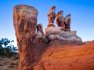 Tall weathered sandstone hoodoos and sculpted rock formations glow in warm sunset light at Devil’s Garden.