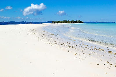 Expansive white sandbank at Nosy Iranja, Madagascar, bordered by shallow turquoise water and tropical island coastline in the Indian Ocean.