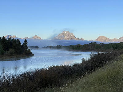 Morning mist over the Snake River at Oxbow Bend with the Teton Range partially above fog, Grand Teton National Park, Wyoming.