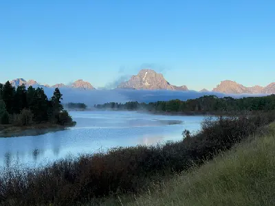 Morning mist over the Snake River at Oxbow Bend with the Teton Range partially above fog, Grand Teton National Park, Wyoming.