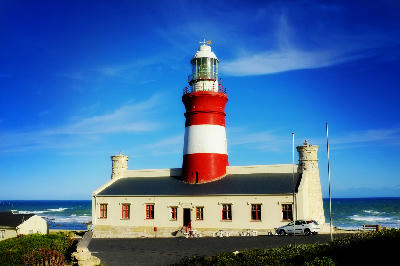 Red-and-white Cape Agulhas Lighthouse beside the ocean at the southernmost point of Africa in South Africa.