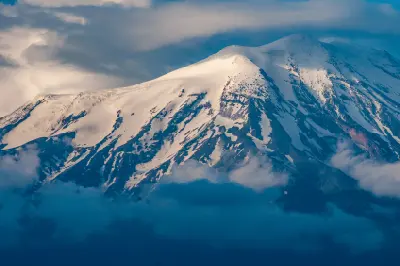 Snow-covered upper slopes and peaks of Mount Ararat emerging through clouds in Eastern Turkey.