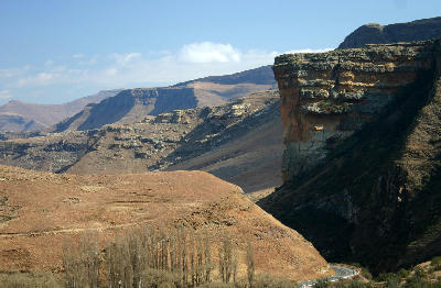 Brandwag Buttress sandstone cliff towering above a winding mountain road in Golden Gate Highlands National Park, with layered highland landscapes stretching into the distance.