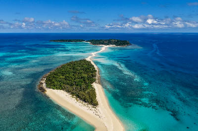 Drone panorama of Nosy Iranja, Madagascar, featuring tropical islands, bright turquoise reef water, white sandbanks, and the iconic sandbar stretching across the Indian Ocean.