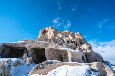Snow-covered rock chambers and pathways at Uçhisar Castle in Cappadocia, Turkey.