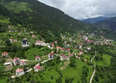 Aerial view of Hamsiköy with red-roofed houses scattered across green mountain slopes near Maçka, Trabzon, Turkey.