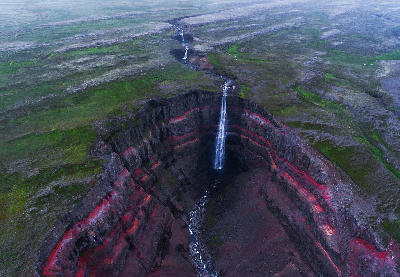 Hengifoss waterfall dropping into a layered red basalt canyon in the Eastfjords, eastern Iceland.