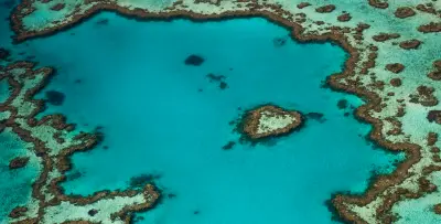 Aerial view of Heart Reef surrounded by turquoise water and larger coral formations in the Great Barrier Reef, Queensland.