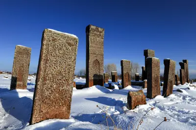 Tall carved Seljuk tombstones surrounded by snow at the historic Ahlat cemetery beneath a clear blue winter sky in eastern Turkey.