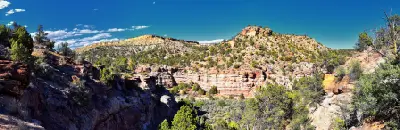 Panoramic view of layered sandstone cliffs, rocky ravines and juniper-covered hills along the hiking trails of Escalante Petrified Forest State Park.