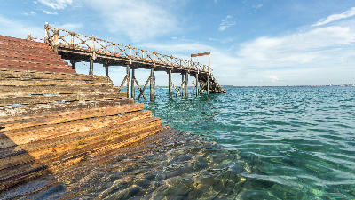 Wooden jetty stretching into the clear turquoise waters surrounding Prison Island near Stone Town, Zanzibar.