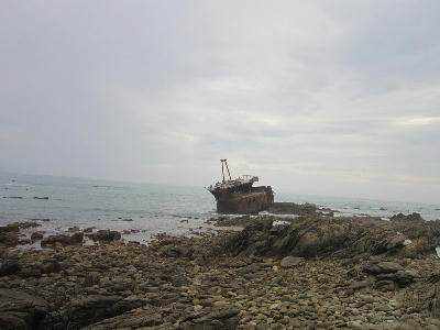 Rusting shipwreck on the rocky shoreline of Cape Agulhas in the Western Cape, South Africa.