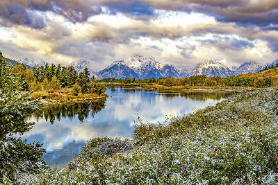 Oxbow Bend reflecting the Teton Range with autumn trees and fresh snow under dramatic clouds, Grand Teton National Park, Wyoming.