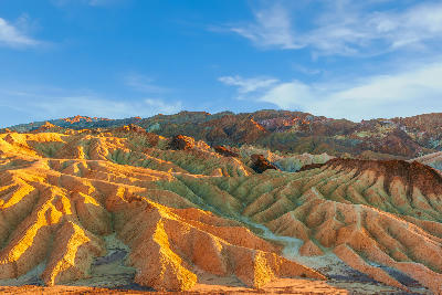 Zabriskie Point at sunset in Death Valley National Park California with golden eroded ridges and colorful badlands landscape
