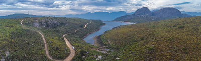 Drone panorama of Paarl Mountain Nature Reserve showing granite rock formations, fynbos-covered hills, winding gravel roads, and a mountain reservoir near Paarl in South Africa’s Cape Winelands.