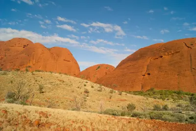 Red sandstone domes of Kata Tjuta rising above spinifex grassland under a blue sky in Northern Territory, Australia.