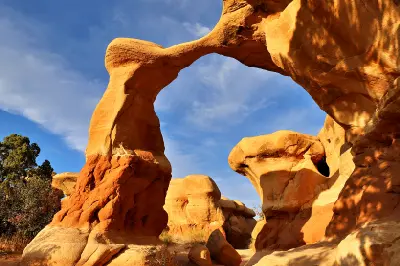 Metate Arch spans between sculpted sandstone formations glowing in warm sunlight at Devil’s Garden.