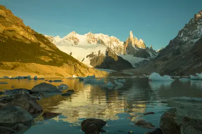Sunrise at Laguna Torre with icebergs floating on the lake and Cerro Torre peaks reflected in calm water, Patagonia, Argentina.
