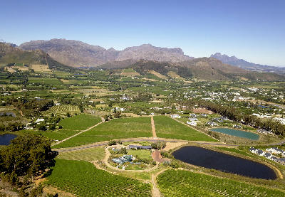 Aerial panorama of Franschhoek with vineyards, farmland and mountain scenery in the Cape Winelands of South Africa.