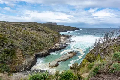 Rugged coastline and turquoise water at Maingon Bay near Remarkable Cave, Tasman Peninsula, Tasmania.