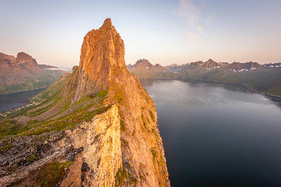 Segla mountain ridge at sunset, Senja Norway, overlooking Mefjorden fjord with steep cliffs and surrounding alpine peaks.