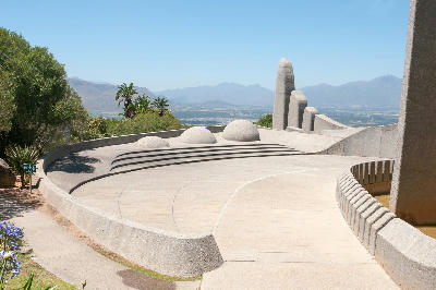 Curved amphitheatre-style terraces and abstract concrete structures at the Afrikaans Language Monument in Paarl, South Africa, with mountain views across the Cape Winelands under a clear blue sky.