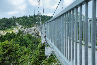 Metal suspension bridge crossing above forest and granite cliffs on Grandfather Mountain in North Carolina.