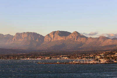 Gordon's Bay harbour and coastline beneath the Hottentots Holland Mountains at sunset in the Western Cape, South Africa.