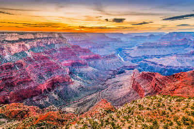 Grand Canyon South Rim at sunset with layered canyon formations and the Colorado River visible in the distance