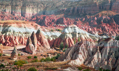 Layered red, pink, and white volcanic rock formations in Red Valley, Cappadocia, Turkey, with sculpted ridges and colourful badlands stretching across the landscape.