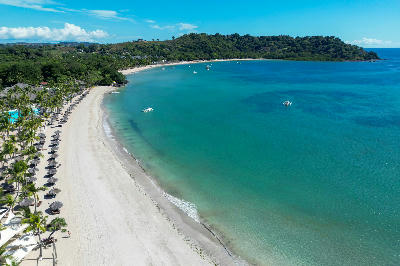 Drone view of Andilana Beach on Nosy Be in Madagascar showing curved white sand beach and turquoise tropical ocean water.