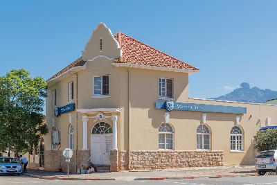 Historic Standard Bank building in Ladismith with traditional Cape-style architecture and mountain peaks visible in the background, Klein Karoo, Western Cape, South Africa.