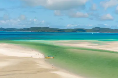Visitors and a small tour boat among white silica sandbars and turquoise shallows at Hill Inlet, Whitsunday Island.
