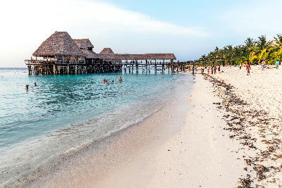 Overwater thatched restaurant on stilts overlooking the calm turquoise waters and white sand of Kendwa Beach, Zanzibar, Tanzania.