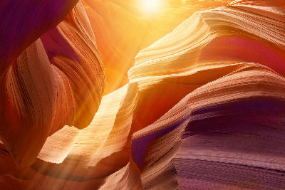 Upper Antelope Canyon in Arizona with bright sunlight streaming through narrow openings, highlighting smooth layered sandstone walls and warm orange tones.