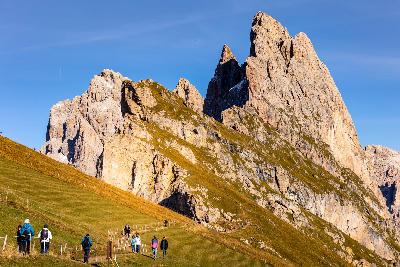 Hikers on Seceda ridge with Odle peaks in Val Gardena, Dolomites, Italy.