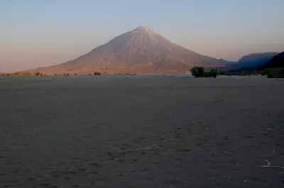 Ol Doinyo Lengai volcano at dawn rising above the dark volcanic plains near Lake Natron in northern Tanzania.