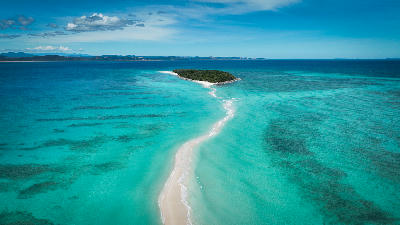Drone view of the Nosy Iranja sandbar in Madagascar with white sand, shallow turquoise water, reef textures, and tropical islands in the Indian Ocean.