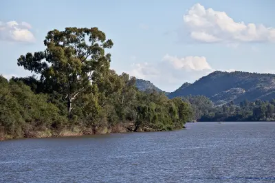 Vaal River bordered by riverine woodland and low mountain ridges in the Vredefort Dome, South Africa.